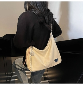 Beige large capacity tote bag shown on model back shoulder in a minimalist indoor setting