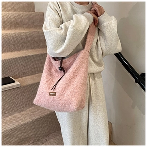 Detalle de bolso tote de felpa rosa con parche de logo en cuero y cordón ajustable