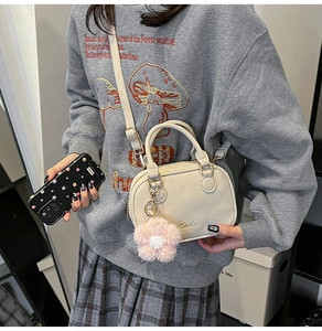 Close-up of cream square pillow bag with matte leather finish and pink plush flower charm