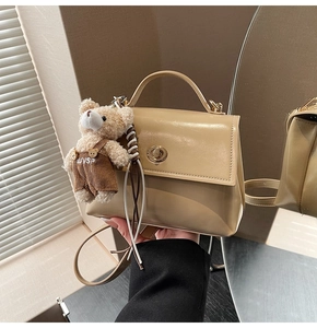 Detail of beige faux leather crossbody bag with metal twist lock and cute bear charm