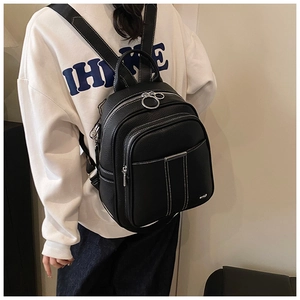 Detail of black pebbled leather backpack with white contrast stitching and silver ring zipper