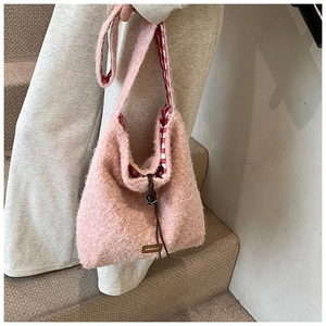 Vista lateral del bolso tote rosa afelpado con forro de cuadros rojos y pequeño cascabel