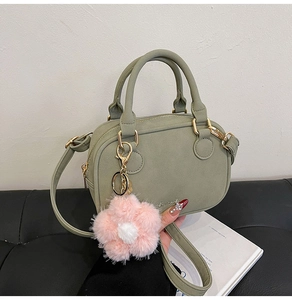 Detail of light green Boston handbag with suede texture and floral plush charm