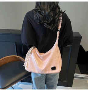 Pink Hobo crossbody bag featuring a soft leather texture and woven black white pendant