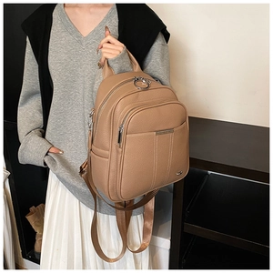 Macro detail of camel pebbled leather backpack with silver zippers and metal hardware