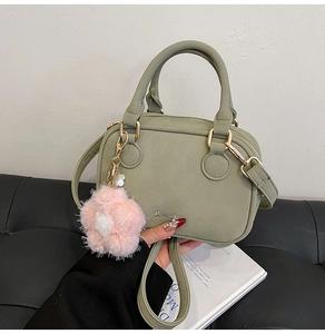 Grass green suede Boston bag with circular handles and plush flower charm detail