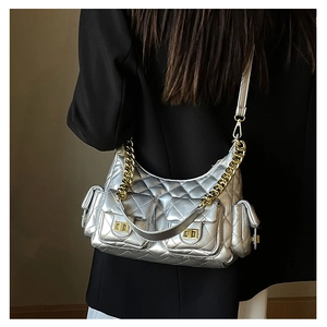 Close-up of metallic silver quilted bag with gold hardware worn on dark blazer