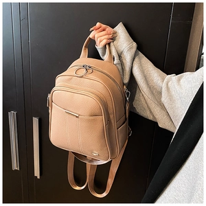 Detail of khaki pebbled leather backpack with silver ring zippers and top handle