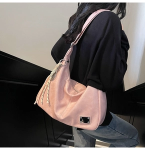 Pink crescent hobo bag with silver metallic plate and woven charm shown on model shoulder
