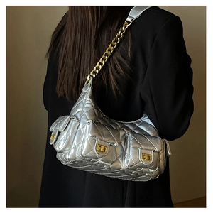 Close-up of silver quilted crossbody bag with gold turn-locks and chain strap detail