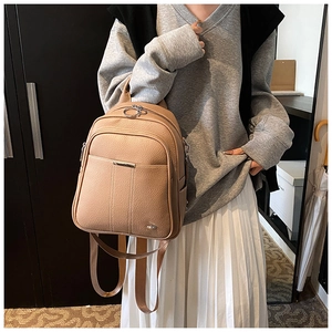 Close-up of a khaki lychee-grain leather backpack worn with a casual gray hoodie