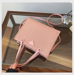 Close-up of pink woven tote bag showing fine cross-weave texture and metal strap rings
