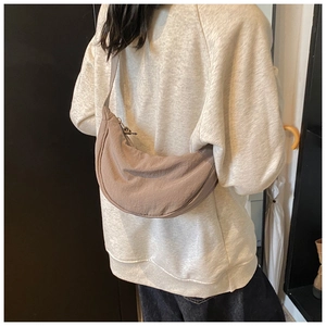 Detail of light brown nylon crescent bag showing smooth texture and wide shoulder strap