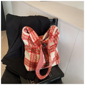 Detalle de bolso tote de felpa a cuadros rojos y blancos sobre blazer negro con libros