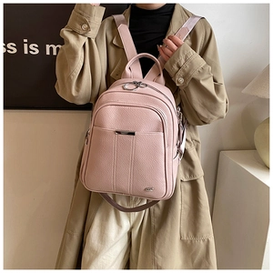 Close-up of pink litchi grain leather backpack with metal bar detail and ring zippers