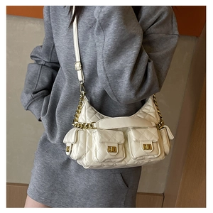 Detail view of the white quilted shoulder bag with golden twist-lock pockets and chain strap