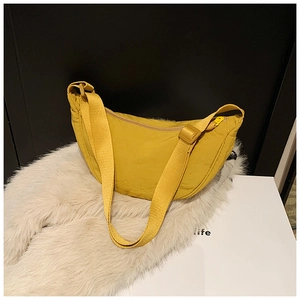 Detail view of the yellow nylon crescent bag featuring adjustable strap and smooth zipper