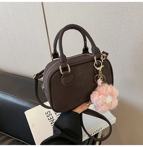 Detail of dark brown leather Boston bag with pink floral charm and gold hardware