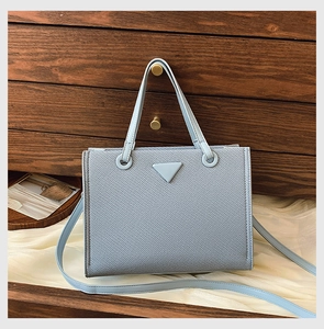 Macro shot of the light blue textured tote bag with iconic triangle emblem detail