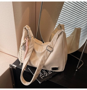 Close-up of beige tote bag with adjustable strap and braided cord decor on a dark surface