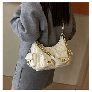 Detailed view of quilted white shoulder bag with gold chain and multi-pocket design