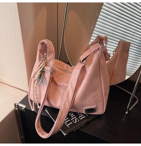Detailed close-up of a pink faux leather tote bag with metallic logo and woven pendant