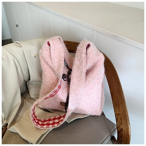 Detalle del bolso tote de felpa rosa con ribete de cuadros y textura suave en silla