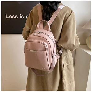 Detail view of the pink lychee leather texture and silver zipper rings on the backpack