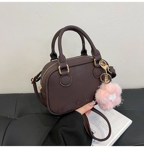 Detail of chocolate brown pillow bag with gold hardware and pink plush flower charm