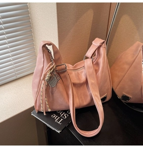 Detail of pink hobo bag featuring badminton racket charm and woven tassel accent