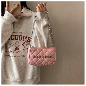 Detail of pink quilted handbag with silver chain strap and metal logo lettering