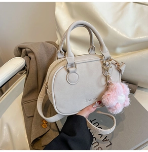 Detail of off-white boston bag with plush flower charm on a minimalist urban background