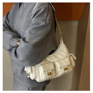 Detail of white quilted handbag with multiple functional pockets and gold chain strap