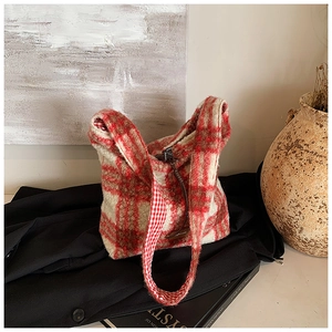 Detalle del bolso tote de felpa con cuadros rojos y blancos sobre abrigo oscuro