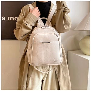 Detail of off-white lychee grain leather backpack with silver metal zippers on model