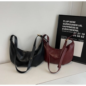 Close-up of black and burgundy hobo shoulder bags with adjustable straps on white surface