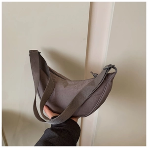 Detail of adjustable woven strap and grey nylon fabric texture on half-moon bag