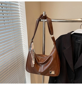 Detail of vintage dark brown faux leather hobo bag with unique tennis racket pendant