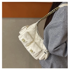 Close-up of white quilted underarm bag featuring gold chain and dual pockets