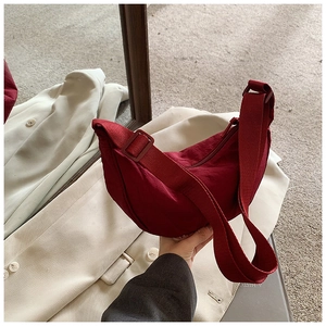 Detail view of burgundy nylon crescent bag with adjustable wide strap and zip top
