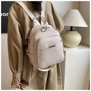 Detail of creamy white pebble leather backpack featuring metal ring zippers and multi-layers