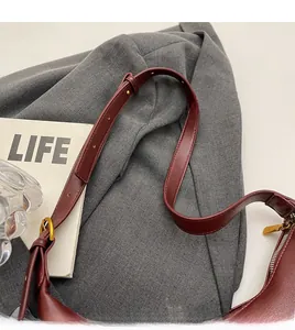 Detail of burgundy leather shoulder strap with gold buckle and stitching for a chic handbag