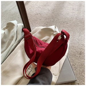 Detail of red nylon crescent bag featuring adjustable wide shoulder strap and zipper