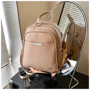 Detail of khaki pebbled leather backpack showing dual zipper structure and mirror reflection