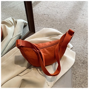 Detail of orange nylon crescent bag with wrinkled texture and wide shoulder strap