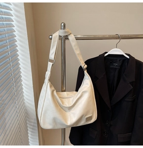 Detail of white PU leather hobo bag with adjustable strap and metal hardware plaque
