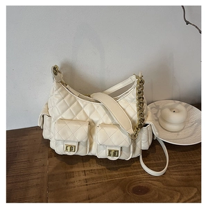 Detailed shot of cream quilted shoulder bag with gold twist locks on wooden table