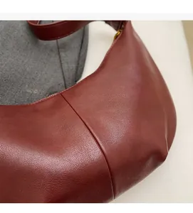 Close-up of wine red half-moon tote bag with vertical stitching and smooth leather texture