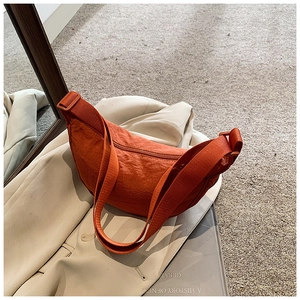 Detailed top view of a burnt orange crescent nylon shoulder bag with adjustable strap