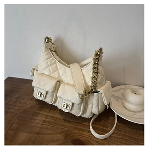 Close-up of beige quilted shoulder bag featuring multiple pockets and gold chain detail